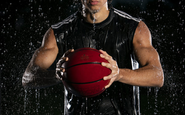 Basketball player in rain on basketball court