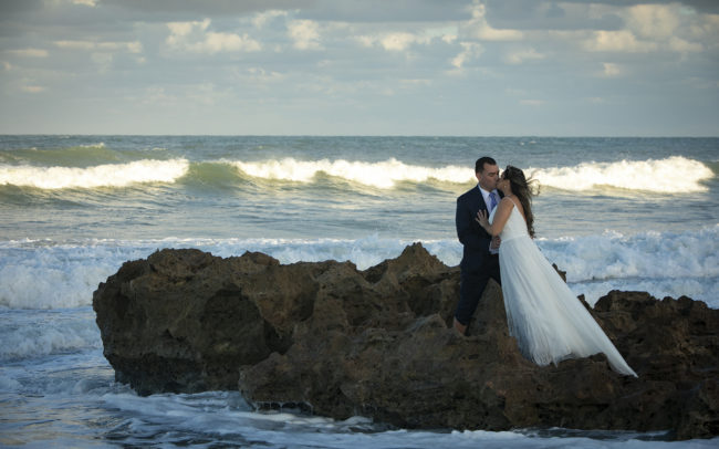 Bride and groom kissing on the rocks at Coral Cove Park in Tequesta, Florida