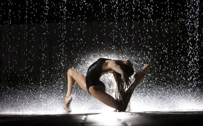 Dancer on knee arching back in the rain
