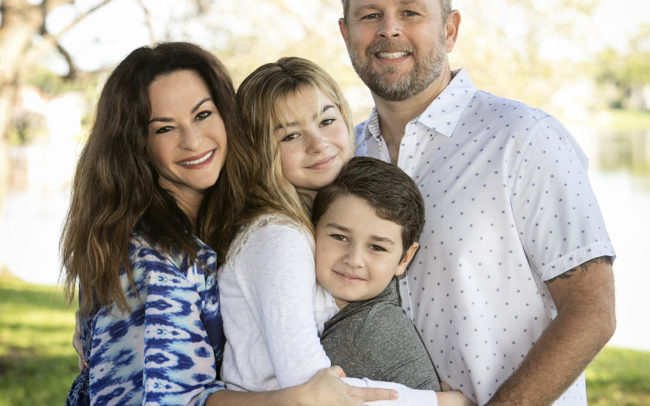 Family portrait standing hugging in park in Wellington, Florida