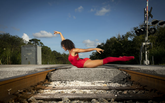 Dancer in red leotard on railroad tracks