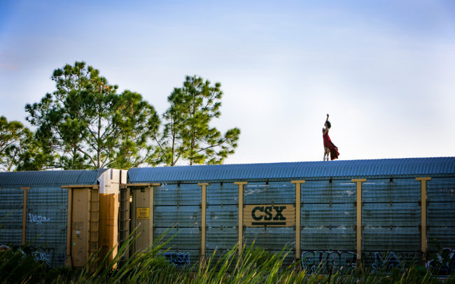 Dancer in red dress on top of freight train