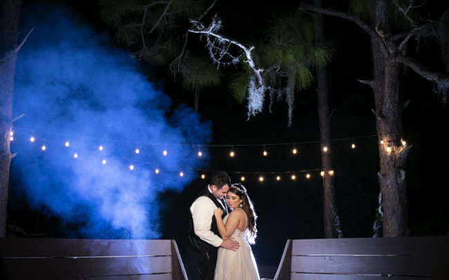Bride and groom hugging behind fire pit at Ever After Farms Ranch Wedding Barn in Indiantown, Florida